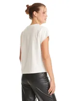 Blusa de crepe color blanco, con cuello redondo y mangas cortas. Presenta apliques de perlas decorativas en el borde del cuello y en los extremos de las mangas.