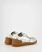 Championes plateados de cuero con detalles en blanco, suela marrón y cordones blancos.