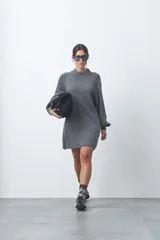Vestido corto de punto color gris, con cuello redondo alto, mangas largas con volumen y puños ajustados. Presenta un diseño de silueta relajada y tejido de textura suave.