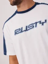 Remera negra de algodón con corte en hombros y mangas, cuello redondo gris oscuro y ribete blanco en los hombros. Estampado frontal con el texto "RUSTY" en tipografía futurista blanca con borde gris.