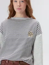 Remera de manga larga a rayas con diseño de bloques de color, cuello redondo y logo bordado en el pecho. Presenta un calce holgado y detalles de pespuntes en los hombros.