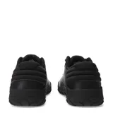Zapatos Caterpillar modelo Hex + Cuero, color negro, estilo sneaker de caña baja con cordones. Presentan una capellada de cuero liso y textil, con suela de goma gruesa con patrón hexagonal en relieve. El logo Caterpillar en amarillo se encuentra en el lateral.