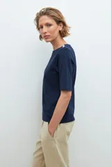 Remera de manga corta color azul marino con escote barco y botones metálicos decorativos en ambos hombros.