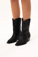 Bota de caña media con diseño estilo western, confeccionada en cuero con acabado texturado tipo craquelado. Cuenta con taco medio y tiradores laterales para facilitar el calce.