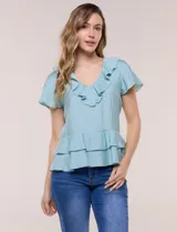 Blusa de satén texturizado color celeste, con escote en V y volados en el cuello, mangas cortas y dobles volados en el bajo estilo péplum.