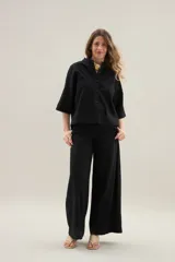 Camisa de lino de calce relajado, color negro, con cuello mao, mangas cortas y bajo redondeado con aberturas laterales.