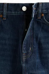 Jean de denim azul oscuro con diseño de piernas curvas y corte holgado de tiro medio.