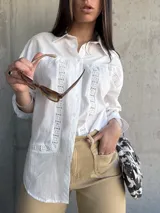 Camisa blanca de manga larga con detalles de encaje en el frente y en los puños.