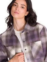 Camisa de manga larga de franela con estampado a cuadros en tonos violeta, gris y blanco, de corte relajado, con bolsillos en el pecho y cierre frontal de botones.