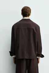 Sobrecamisa de corte regular confeccionada en tejido de mezcla de lyocell y algodón. Presenta cuello con solapas de muesca, cierre frontal con botones, mangas largas con puños abotonados y bolsillos de vivo en la parte frontal.