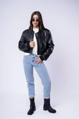 Campera estilo bomber de cuero sintético en color negro, con cierre frontal, cuello, puños y ruedo acanalados. Presenta un diseño corto y holgado.