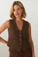 Chaleco sastre marrón con escote en V, cierre frontal con botones y falsos bolsillos. Confeccionado en lana fina sin teñir.