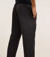 Pantalón deportivo gris oscuro con cintura elástica, bolsillos con cremallera, textura y estampa lettering.