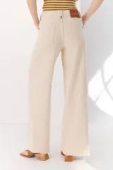 Pantalón de algodón color crema, de corte palazzo, tiro alto y ruedo desflecado. Incluye cinturón marrón con hebilla circular dorada.