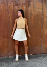 Falda corta tipo wrap de cuero color crudo, con diseño cruzado y ajuste mediante tiritas laterales.
