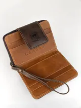 Mini billetera de cuero con diseño combinado de cuero liso marrón y cuero con pelo vacuno estampado. Cuenta con cierre de solapa con broche magnético y logo de búho grabado, además de una correa de muñeca extraíble.