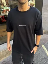 Remera de algodón pesado en color negro, con corte oversize y cuello redondo. Presenta un pequeño logo estampado en blanco en el centro del pecho.