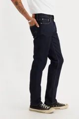 Pantalón de jean corte slim fit, color azul oscuro, con cierre de botón y cremallera, y bolsillos laterales y traseros.