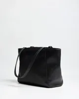 Cartera tipo tote bag de cuero sintético negro, con doble asa de hombro y detalles de tachas metálicas plateadas en los laterales frontales.