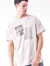 Remera color arena con cuello redondo y estampado pequeño en el pecho.
