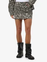 Pollera mini de tiro bajo confeccionada en sarga de algodón con estampado animal print de cebra y corte recto.