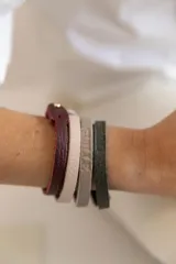 Pulsera de cuero vacuno color borgoña con broche dorado, pulsera de cuero vacuno color rosa pálido, pulsera de cuero vacuno color gris con la palabra "Guiller" grabada y pulsera de cuero vacuno color verde oscuro con la palabra "Enzo" grabada.