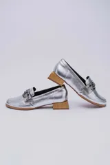 Mocasines de cuero en tono bronce metalizado, con detalle de aplique metálico dorado en el empeine y taco cuadrado bajo de madera.