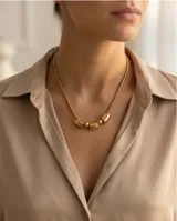 Collar de acero dorado con cadena tipo serpiente y dije central compuesto por tres piezas cilíndricas intercaladas con dos esferas pequeñas.