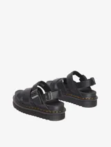 Sandalia Dr. Martens Voss II Athena de dos correas, color negro, con diseño minimalista y elegante. Confeccionada en cuero Athena recubierto de PU, cuenta con una suela Quad Zebrilus de 3 pulgadas y dos hebillas de metal en el tobillo para un ajuste cómodo. Presenta la costura amarilla característica de Dr. Martens.