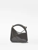 Bolso de cóctel Adolfo Domínguez de estructura rígida y acabado brillante. Presenta un diseño asimétrico con asa tubular integrada y correa larga extraíble. Cuenta con cierre magnético y logo de la marca estampado en dorado.