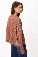 Sweater de punto con diseño de rayas verticales en relieve y textura trenzada, color terracota y beige. Presenta cuello redondo, corte holgado y diseño cropped.
