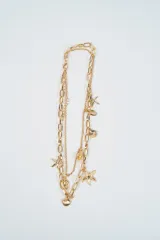 Collar doble de cadena dorada con dijes colgantes con motivos marinos, incluyendo estrellas de mar y caracoles.