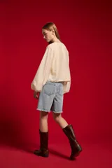 Blusa de lyocell color natural, holgada y de manga larga, con cuello redondo, detalles de encaje y lazo para anudar en el frente.