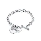 Pulsera de eslabones gruesos en acero quirúrgico color plata, con dijes colgantes en forma de corazón, uno liso y otro con incrustaciones.