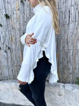 Polerón blanco de morley con cuello alto y volados en ruedo y puños.