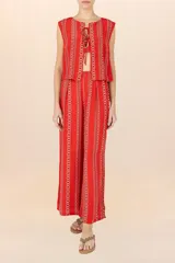 Chaleco sin mangas de color rojo con estampado de cadenas doradas en disposición vertical. Presenta escote redondo y cierre frontal mediante cordones entrelazados.