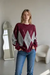 Sweater de tejido de punto con diseño de rombos en contraste, cuello redondo y mangas largas. Presenta una textura suave y un corte holgado.