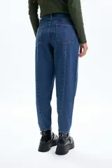 Jean de corte slouchy en color azul, con diseño de costuras visibles y cortes en las piernas. Presenta un tiro alto y una silueta holgada que se estrecha hacia los tobillos.