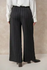 Pantalón de corte ancho y tiro alto, confeccionado en tejido azul marino con finas rayas verticales de hilo de lurex plateado. Presenta cintura con pasacintos y se incluye un cinturón negro con hebilla metálica.