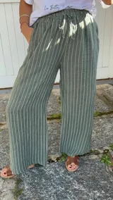 Pantalón de corte ancho y relajado, confeccionado en lino con diseño de rayas verticales. Presenta cintura elástica con cordón de ajuste y bolsillos laterales.