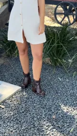 Botas cortas de cuero color marrón oscuro con hebillas y estribo desmontable.