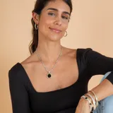 Collar con cadena de eslabones trenzados en plata con detalles en oro, que sostiene un dije circular con piedra ónix negra central y borde en oro.