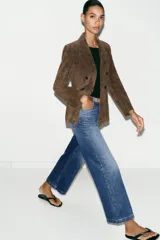 Jeans de tiro alto con pernera ancha y corte cropped. Presenta diseño de cinco bolsillos, cierre frontal con cremallera y botón, e incluye un cinturón oscuro con hebilla metálica.