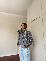 Campera puffer con estampado de leopardo en tonos blanco y negro, cuello alto, cierre frontal y bolsillos laterales.