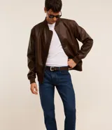 Pantalón de jean azul oscuro para hombre, con corte slim, diseño clásico de cinco bolsillos, trabillas para cinturón y cierre frontal con botón y cremallera.