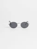 Lentes de sol con montura metálica plateada y lentes ovaladas oscuras, con protección UV.