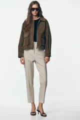 Pantalón de tiro alto color beige, con detalle de costuras marcadas en el delantero y la espalda. Incluye bolsillos delanteros de vivo y cierre frontal con cremallera, botón interior y gancho metálico.