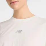 Remera deportiva New Balance color blanco hueso, de corte holgado y largo por encima de la cintura. Tiene cuello redondo, mangas cortas y logo estampado en el pecho.