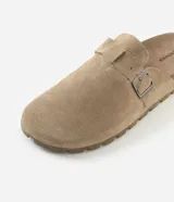 Ojota mule de cuero con acabado de gamuza color marrón, diseño cerrado en la parte delantera con hebilla metálica lateral ajustable y suela dentada de goma.