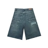 Bermuda de jean estilo baggy, color azul oscuro con efecto lavado. Presenta un corte holgado, bolsillos traseros amplios y un bordado decorativo con diseño de llamas y texto en uno de los bolsillos.